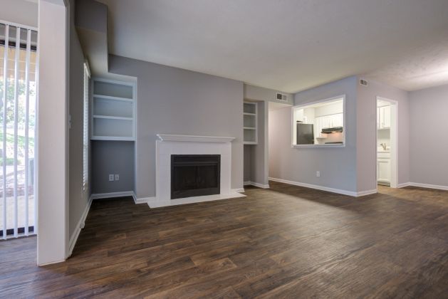 Spacious living room with wood floors, fireplace, open kitchen, and sliding glass door to the outside.