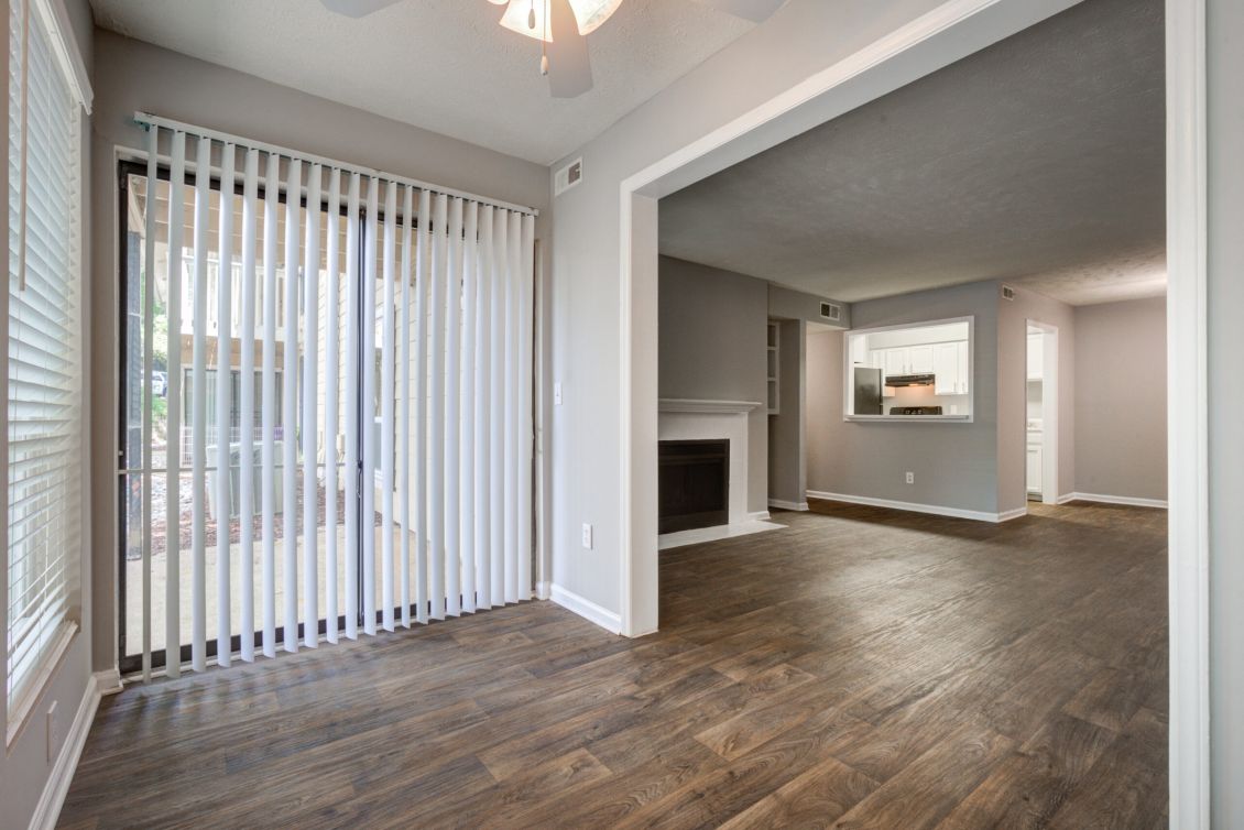 Open living and dining area with wood floors, sliding glass door, fireplace, and a view into the kitchen.